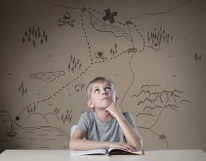 Little kid thinking about treasure map from his adventure book
